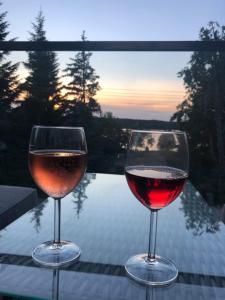 due bicchieri di vino seduti su un tavolo con il tramonto di Luksusowy apartament Charzykowy a Charzykowy