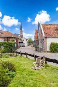 a chair on the grass in a village with a church at Authentic apartment in farmhouse near Amsterdam in Ilpendam