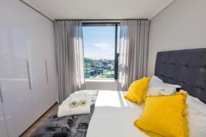a bedroom with a bed with yellow pillows and a window at Magnificent penthouse with breathtaking views in Cape Town