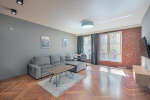 salon z szarą kanapą i ceglaną ścianą w obiekcie ApartMate- Perfect Apartment Oldtown Gdansk w Gdańsku