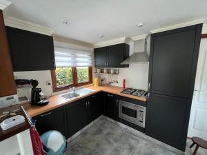 uma cozinha com armários pretos e um lavatório em Chalet 58 ''Pollie'' em Hattemerbroek