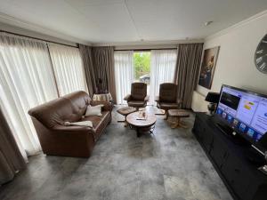 a living room with a couch and a flat screen tv at Chalet 58 ''Pollie'' in Hattemerbroek