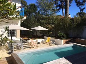 a pool with chairs and umbrellas next to a house at Villa Arcachon, 6 pièces, 8 personnes - FR-1-374-147 in Arcachon