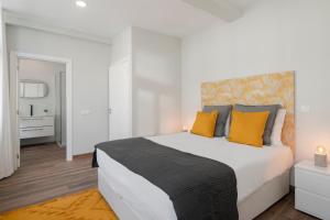a white bedroom with a large bed with yellow pillows at Alegria Flat by An Island Apart in Funchal