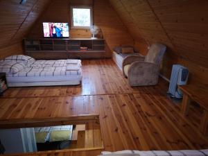 a attic room with a couch and a chair in a cabin at domki nad jeziorem, las, do 10 osób jezioro Wilczyńskie Budzisławskie - domek letniskowy osobno ogrodzony, ogrzewany - wielkopolska, 62-550 Zygmuntowo gm Wilczyn in Zygmuntowo