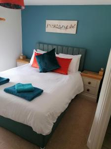 Una cama con almohadas rojas y azules. en The Prince of Wales, en Helston