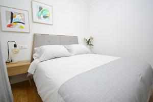a bedroom with a white bed and a wooden table at Apartamento frente al mar en Cambados in Cambados
