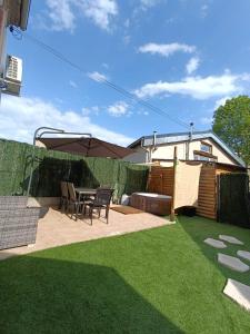 a patio with a table and chairs under an umbrella at Maison Althéa - Calme, Spa & Extérieur plein sud in Lempty