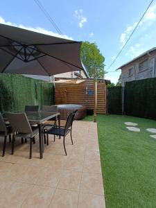 eine Terrasse mit einem Tisch, Stühlen und einem Sonnenschirm in der Unterkunft Maison de campagne & SPA, Barbecue, Clim, WIFI 
