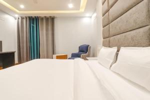 um quarto com uma cama branca e uma cadeira azul em FabHotel Av Royale em Dehradun