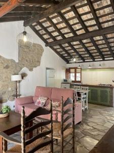 sala de estar con sofá rosa y cocina en La casa vieja de Marchenilla, en Jimena de la Frontera