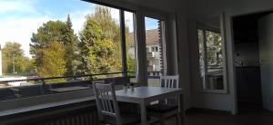 a table and chairs in a room with a large window at Frisch renoviertes Appartement in Mönchengladbach