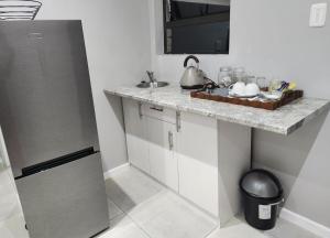 a kitchen with a counter with a sink and a refrigerator at Clear Corner Suites in East London