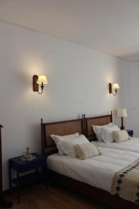 two beds in a bedroom with two lamps on the wall at Boutique Inn & Restaurant - Casa dos Suécos in Figueira da Foz