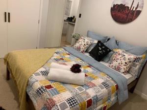 a bed with a quilt and pillows on it at Cute and Cozy near Airport in Auckland