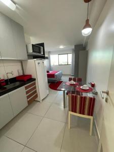 a kitchen and living room with a table and a refrigerator at Flat Lindo e Aconchegante in Recife