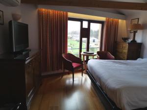 a hotel room with a bed and a tv and a window at La Roseraie. Gaume-Ardenne-lacuisine sur Semois. in Florenville