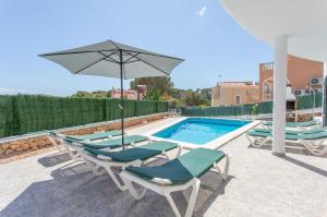 - une piscine avec 2 chaises longues et un parasol dans l'établissement Villa Azucena by Sonne Villas, à Cala Galdana