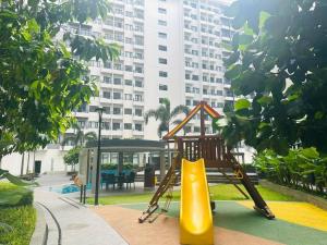 un parque infantil con un tobogán en un parque con un edificio en Condotel Vibe at Spring Residences near Airport, en Manila