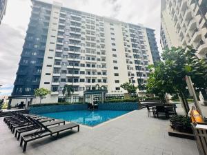 un gran edificio con piscina frente a un edificio en Condotel Vibe at Spring Residences near Airport, en Manila