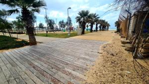 a wooden boardwalk with palm trees on the beach at אשדוד מול הים in Ashdod
