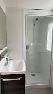 La salle de bains blanche est pourvue d'une douche et d'un lavabo. dans l'établissement MobilHome 2 chambres 229 dans Camping 4 étoiles, à Pont-Aven