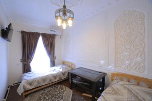 a bedroom with two beds and a table and a chandelier at Hotel Hanifa in Bukhara
