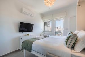 Green Oasis in Parede by LovelyStay في باريد: غرفة نوم بيضاء مع سرير كبير وتلفزيون