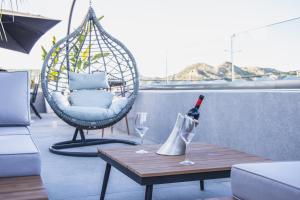 a bottle of wine and two glasses on a balcony at JnS Faliraki Penthouse in Kallithea Rhodes