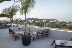 a patio with chairs and a palm tree on a balcony at JnS Faliraki Penthouse in Kallithea Rhodes