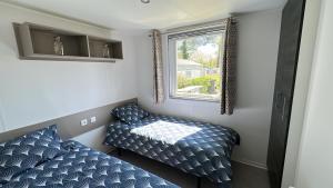 a small room with two beds and a window at MobilHome 2 chambres 229 dans Camping 4 étoiles in Pont-Aven +19 photos
