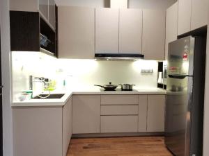 cocina con armarios blancos y nevera de acero inoxidable en Geo 38 Residence Genting Highland, en Genting Highlands