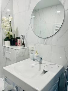 a white bathroom with a sink and a mirror at Apartamentai Sandra in Klaipėda