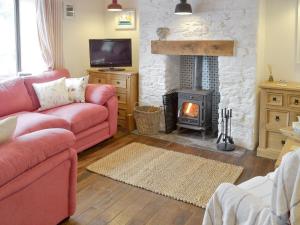 a living room with a red couch and a fireplace at Honeysuckle Bay Cottage in Brixham
