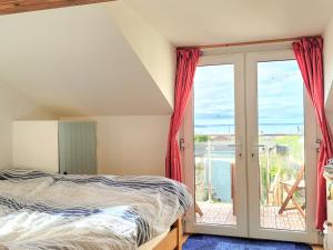 a bedroom with a bed and a sliding glass door at Honeysuckle Bay Cottage in Brixham