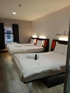 a hotel room with three beds and a window at easyHotel Leeds in Leeds