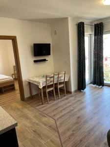 a living room with a table and chairs and a television at Baltic Vip Nowe Apartamenty blisko plaży in Rewal