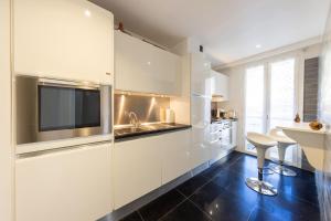 a kitchen with white cabinets and a tv on the wall at Elégant appartement proche bord de mer in Beaulieu-sur-Mer