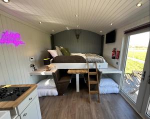 a bedroom in a tiny house with a bed and a desk at The Stag's Head - Shepherds Hut in Great Singleton