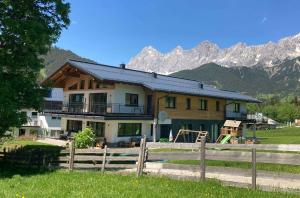 a house with a fence in front of a mountain at Appartements Blumenwiese in Ramsau am Dachstein