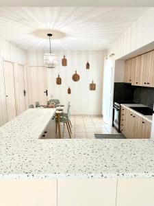 uma cozinha com um balcão branco e uma mesa em Anastasias house near Athens airport em Spata