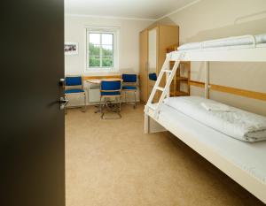 a room with bunk beds and a table and chairs at Sjoa Gjestehus & Vandrerhjem in Otta