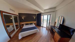 a bedroom with a bed and a desk and a television at Ohtels Gran Hotel Almeria in Almería