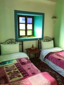 2 camas en una habitación con ventana en Into the Wild HOSTEL en Tacheddirt