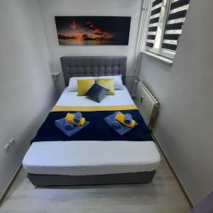 a small bedroom with a bed with yellow and blue pillows at Apartment Alex in Rijeka