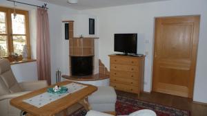 ein Wohnzimmer mit einem TV, einem Sofa und einem Tisch in der Unterkunft Landhaus Riemerfeld in Berchtesgaden