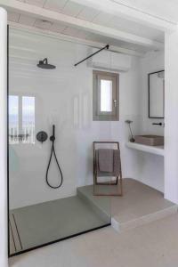ein weißer Raum mit einem Stuhl und einer Glaswand in der Unterkunft Villa Stephanie with heated pool, by Red Windmill Villas in Mykonos Stadt