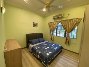 a bedroom with a bed and a fan and a window at Happiness Homestay in Mersing