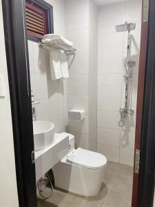 a white bathroom with a toilet and a sink at Thanh Bình Hotel - 47 Y Bih - BMT in Buon Ma Thuot