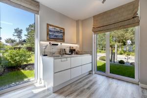 a kitchen with white cabinets and large windows at Ferienhaus Lodino Lodge mit Sauna und Kamin in Loddin
